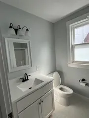 a bathroom with a toilet sink a window and mirror