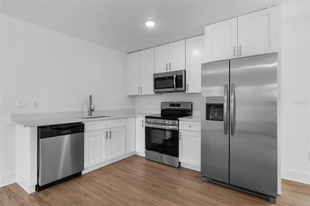 a kitchen with a refrigerator stove and wooden floor