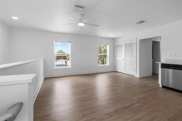 a view of empty room with wooden floor and fan