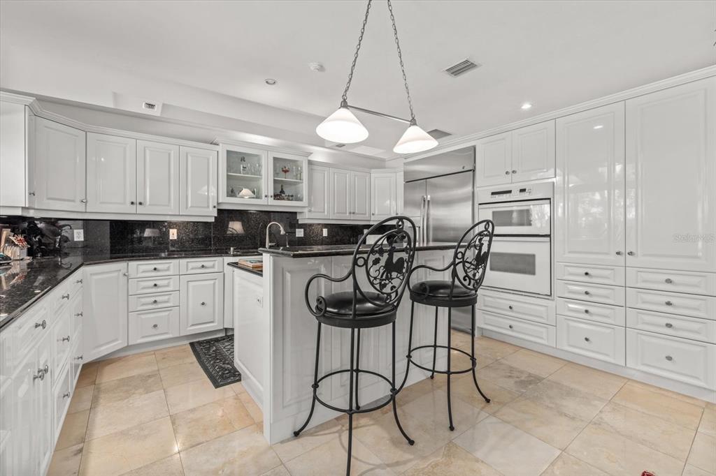 4939 Peregrine Point Way Sarasota, FL 34231 - Photo 21 of 57 a kitchen with stainless steel appliances kitchen island granite countertop a stove a refrigerator and white cabinets with wooden floor