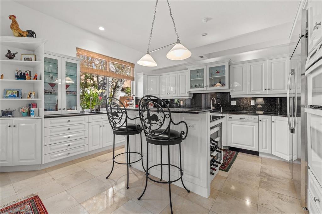 4939 Peregrine Point Way Sarasota, FL 34231 - Photo 22 of 57 a kitchen with stainless steel appliances kitchen island granite countertop a stove a sink a dining table and chairs with cabinets