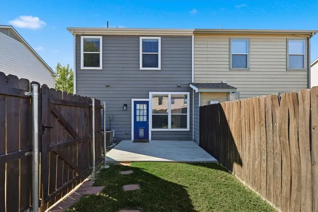 a view of backyard with wooden fence and large windows