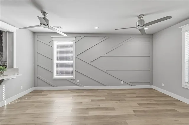 a view of empty room with wooden floor and fan