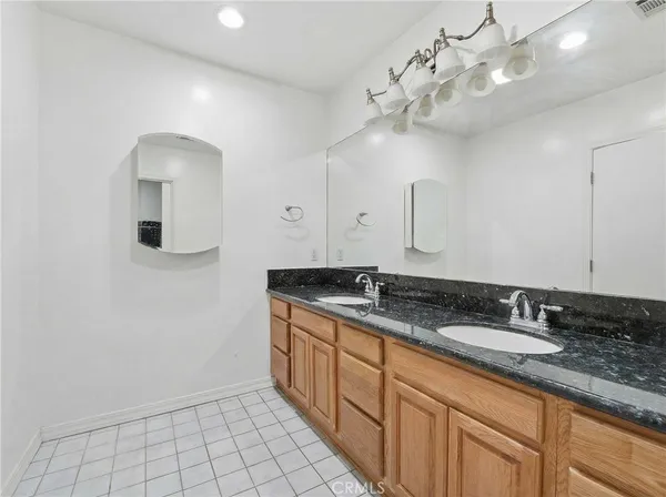 a bathroom with a granite countertop double vanity sink and mirror