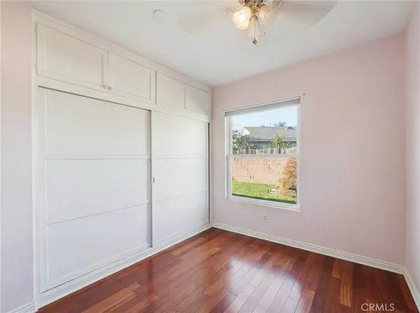 an empty room with wooden floor cabinet and windows