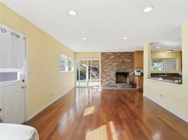 a view of a living room with wooden floor and a fireplace