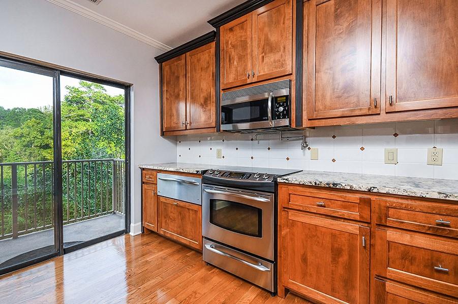 2865 Lenox Road Northeast, Unit 407 Atlanta, GA 30324 - Photo 12 of 27 a kitchen with granite countertop wooden cabinets stainless steel appliances and a large window