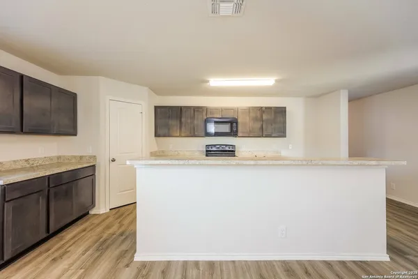 a large kitchen with granite countertop a sink and a stove top oven