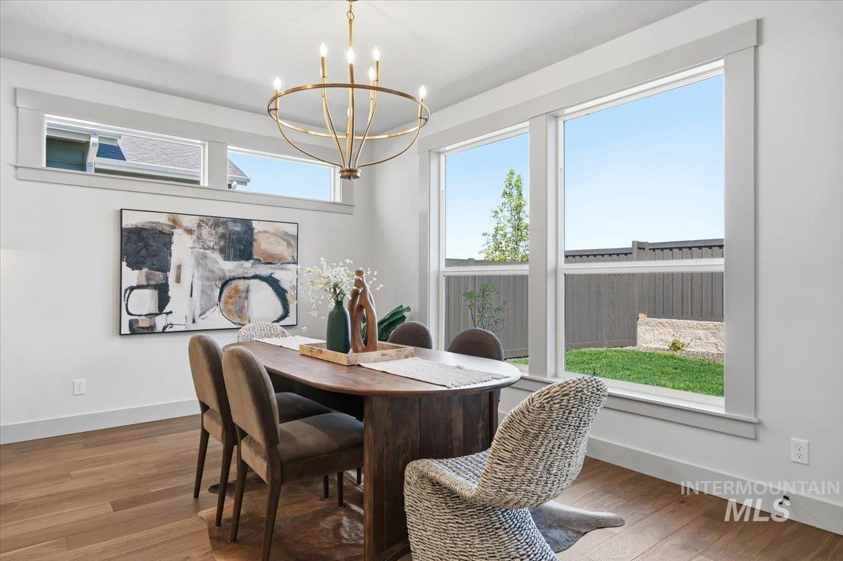 6762 South Messner Way Meridian, ID 83642 - Photo 12 of 35 Open-concept dining area featuring wood-finish flooring, a contemporary chandelier, large windows, and transom windows