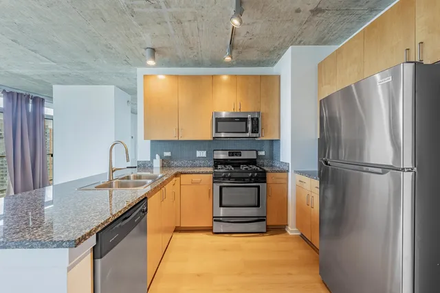 a kitchen with stainless steel appliances granite countertop a refrigerator a sink and a stove