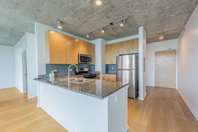 a kitchen with stainless steel appliances granite countertop a sink refrigerator and cabinets