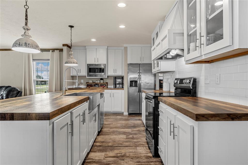 602 3rd Street Abbott, TX 76621 - Photo 14 of 40 Kitchen featuring white cabinetry, wood-finish countertops, subway tile backsplash, stainless steel appliances, and wood-finish flooring