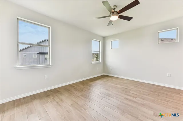 an empty room with wooden floor and ceiling fan