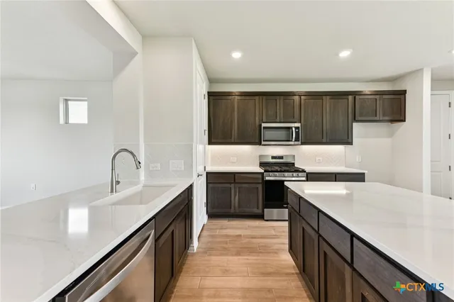 a kitchen with stainless steel appliances granite countertop a sink stove microwave and refrigerator
