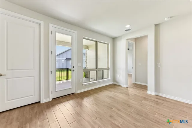 an empty room with wooden floor and windows