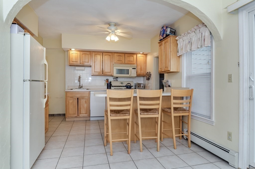 246 Haven Street, Unit 2 Reading, MA 01867 - Photo 7 of 23 a kitchen with granite countertop cabinets and chairs