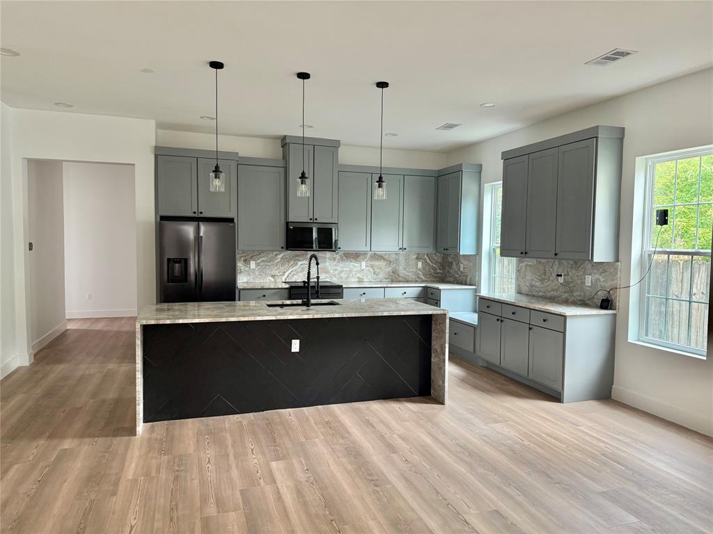 2936 Henry Road Lancaster, TX 75134 - Photo 6 of 28 Kitchen featuring light wood-finish flooring, gray cabinetry, integrated appliances, and a central island with a waterfall countertop
