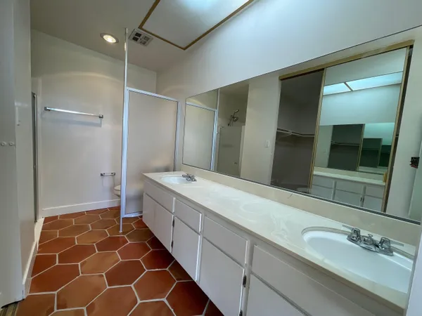a spacious bathroom with a double vanity sink mirror and shower