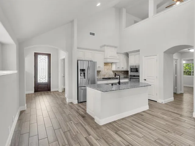 a view of kitchen with stainless steel appliances refrigerator stove and wooden floor