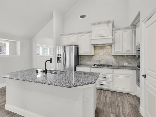 a kitchen with kitchen island granite countertop a sink cabinets and refrigerator