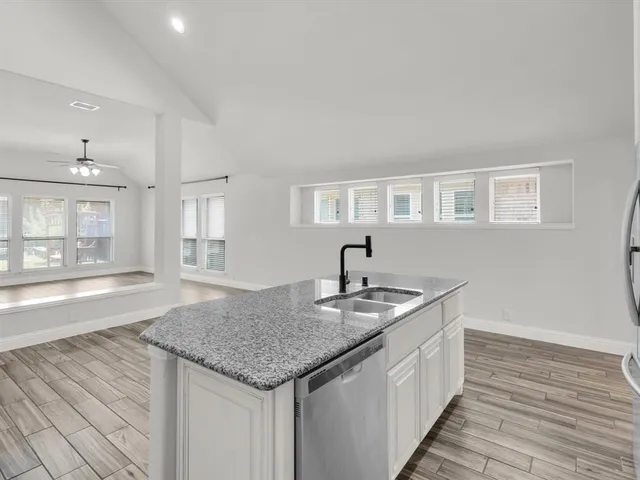 a kitchen with stainless steel appliances granite countertop a sink and dishwasher with wooden floor