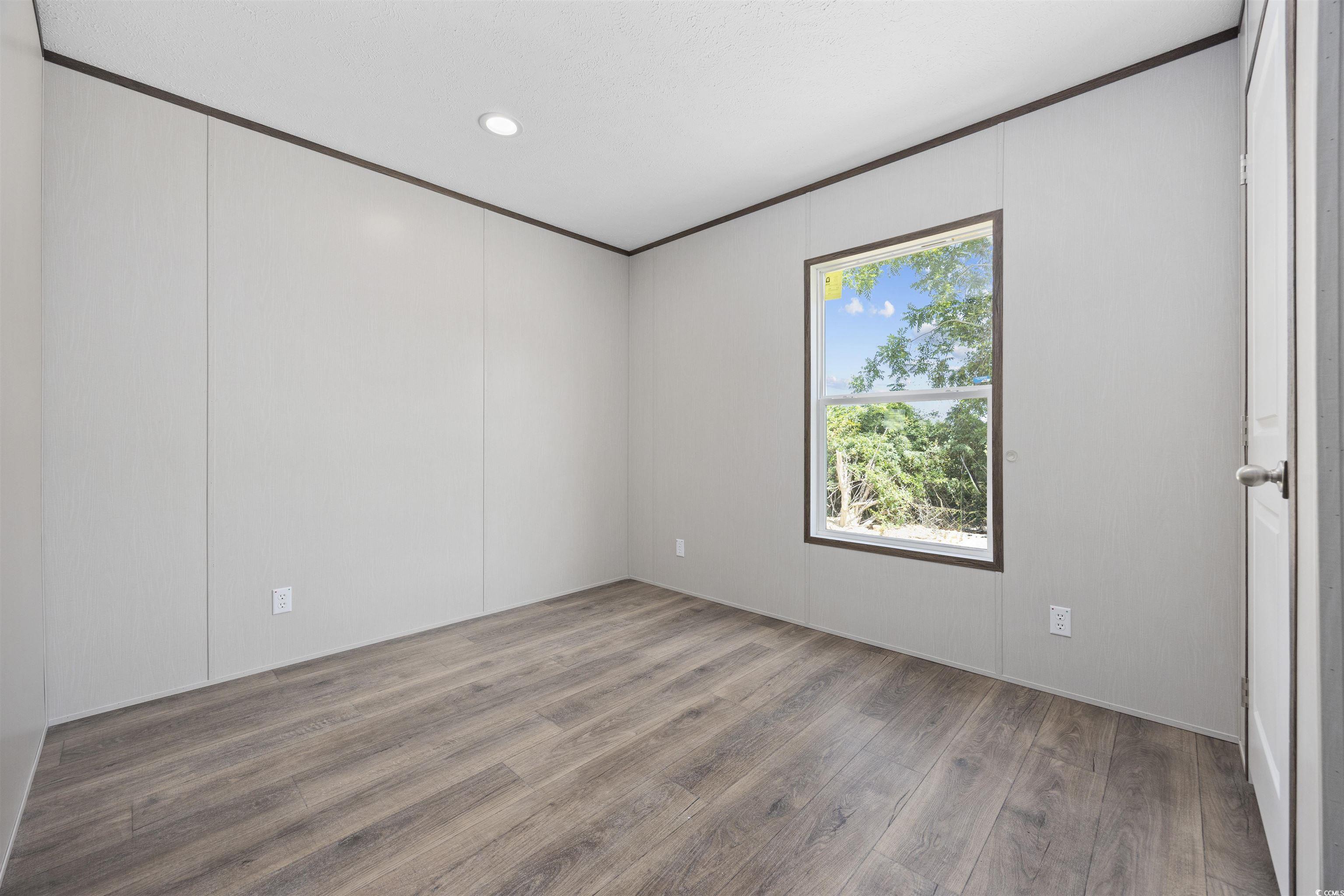 1315 Rabbit Lane Conway, SC 29526 - Photo 22 of 27 Empty room with wood finished floors, ornamental molding, recessed lighting, and a decorative wall