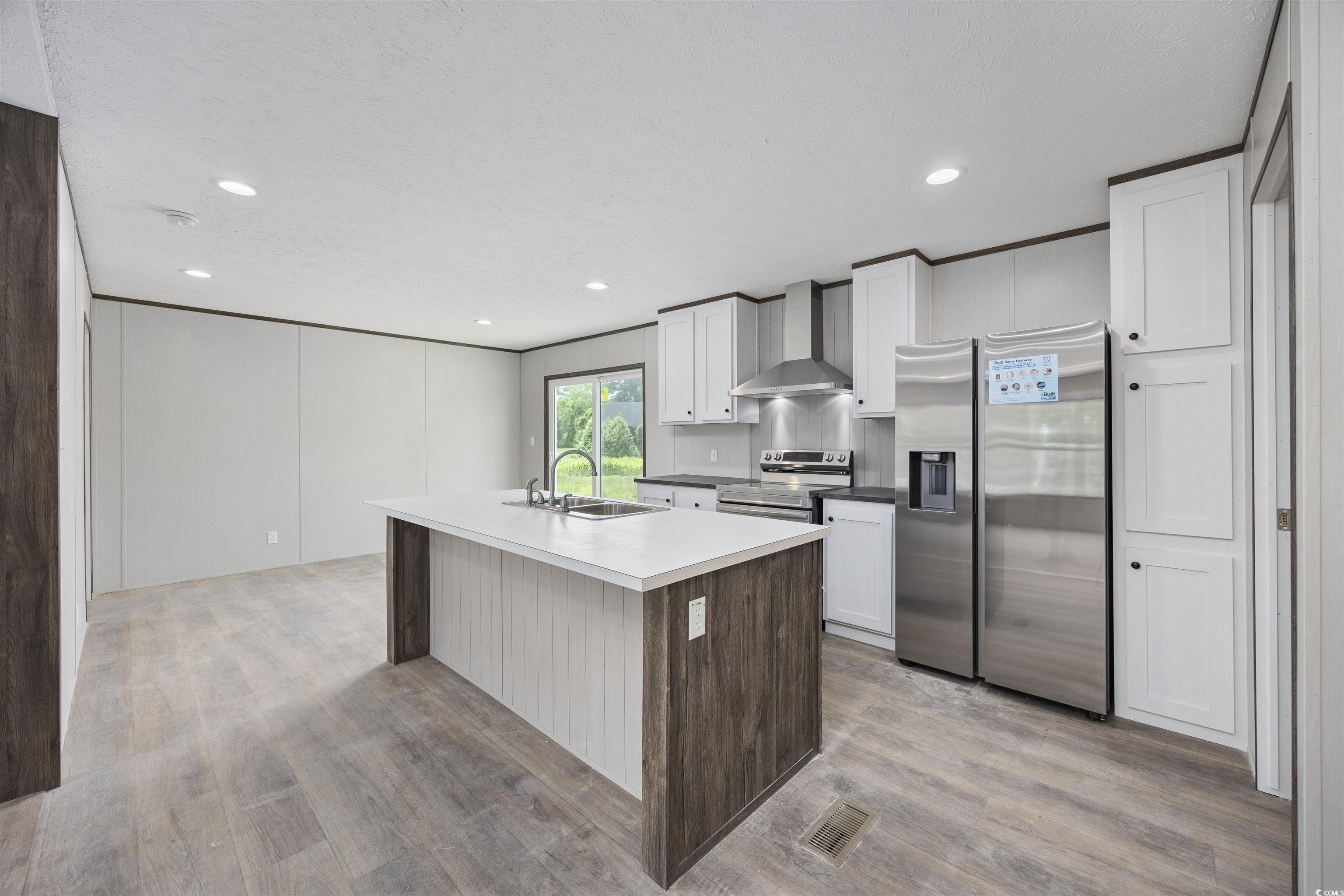 1315 Rabbit Lane Conway, SC 29526 - Photo 8 of 27 Kitchen with appliances with stainless steel finishes, white cabinets, an island with sink, wall chimney exhaust hood, and light wood-style floors