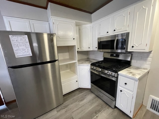 997 Berwin Street Akron, OH 44310 - Photo 19 of 34 Kitchen featuring white cabinetry, stainless steel appliances, crown molding, light countertops, backsplash, and light hardwood floors