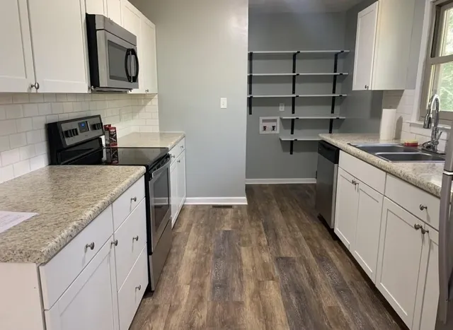 a kitchen with granite countertop a sink stove and refrigerator
