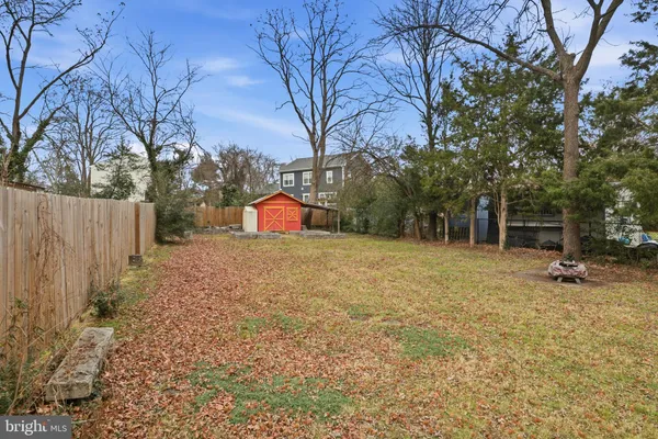 a view of backyard with wooden fence and large trees