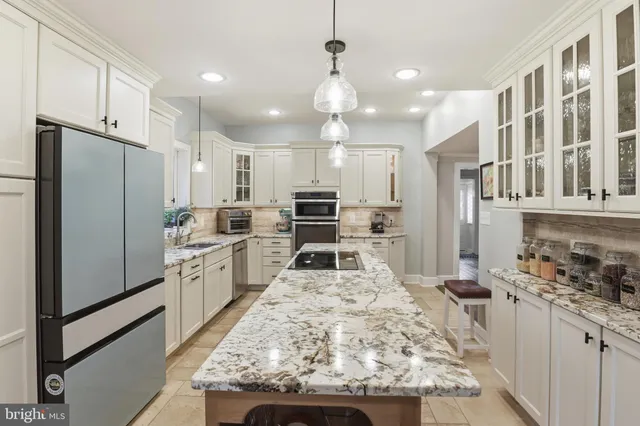 a kitchen with stainless steel appliances kitchen island granite countertop a refrigerator oven a sink dishwasher and white cabinets with wooden floor