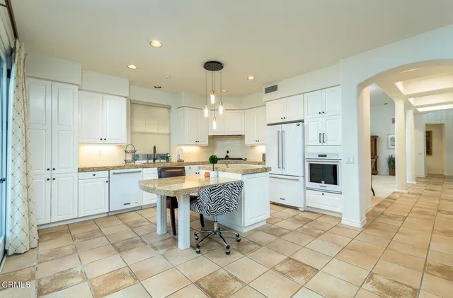 a kitchen with stainless steel appliances kitchen island granite countertop a refrigerator and a sink