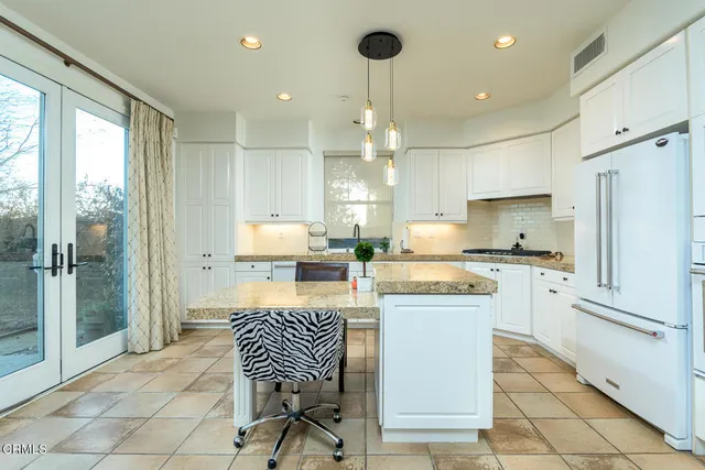 a kitchen with kitchen island granite countertop wooden cabinets and a refrigerator