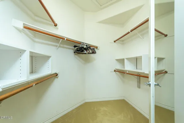 a bedroom with a bed a mirror on the dresser and a large window