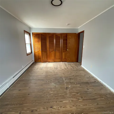 a view of an empty room with window and wooden floor