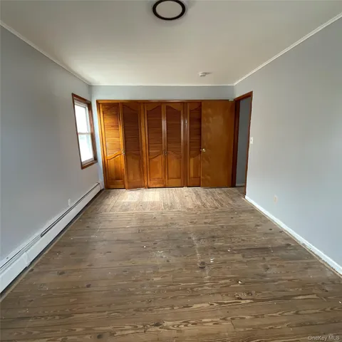 a view of an empty room with window and wooden floor