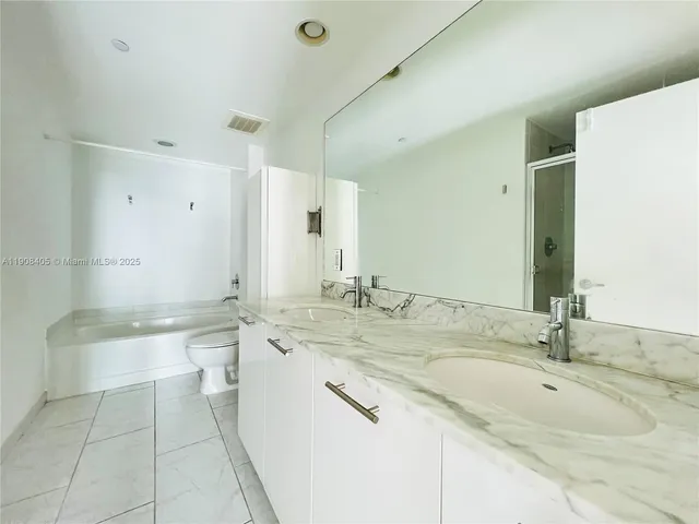 a bathroom with a granite countertop bathtub sink vanity and mirror
