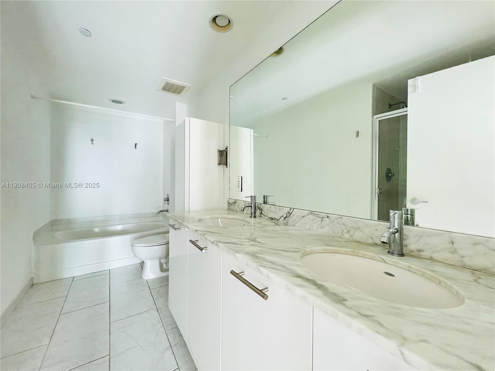 951 Brickell Avenue, Unit 2407 Miami, FL 33131 - Photo 12 of 19 a bathroom with a granite countertop bathtub sink vanity and mirror