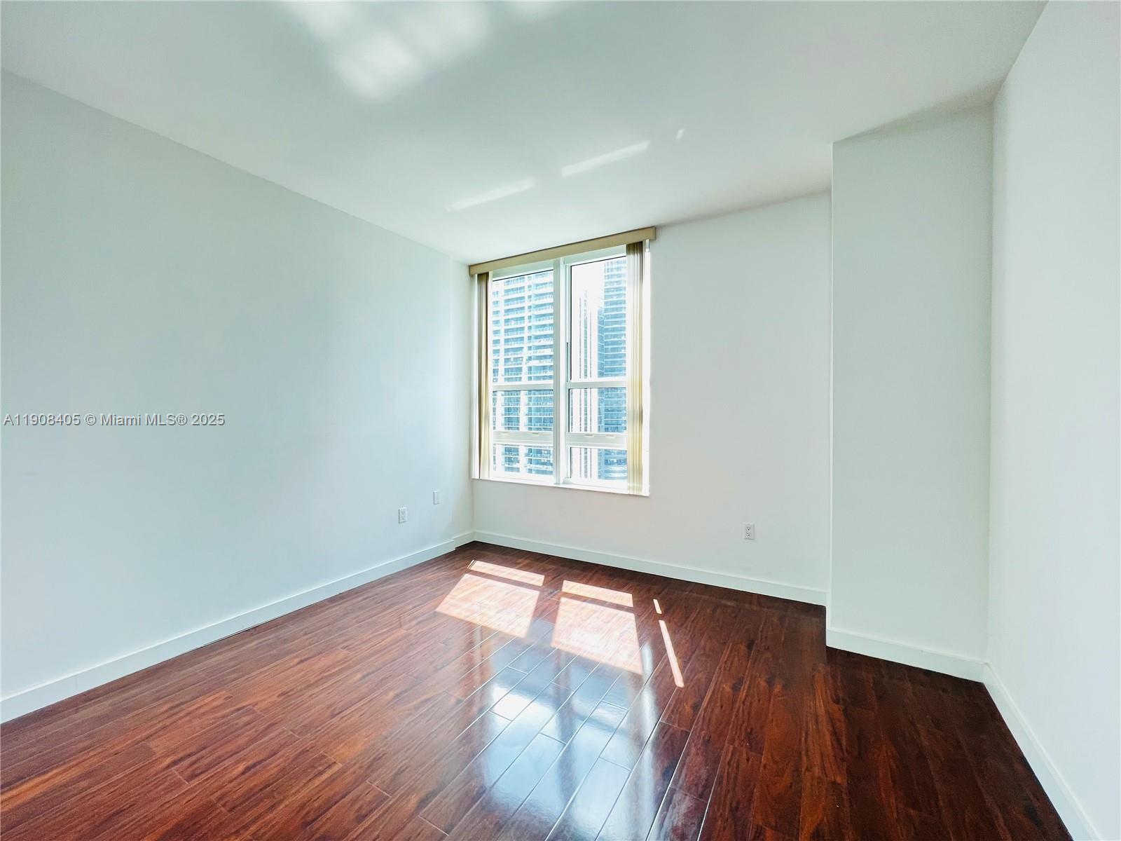 951 Brickell Avenue, Unit 2407 Miami, FL 33131 - Photo 14 of 19 a view of an empty room with wooden floor and a window