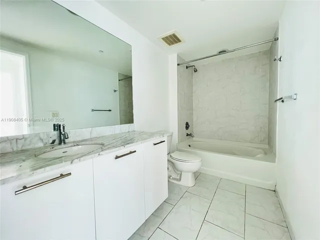 a bathroom with a granite countertop sink a toilet and a mirror