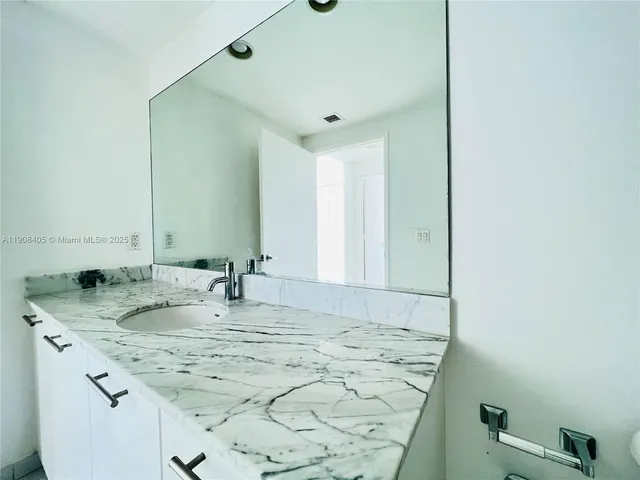 a bathroom with a granite countertop sink and a mirror