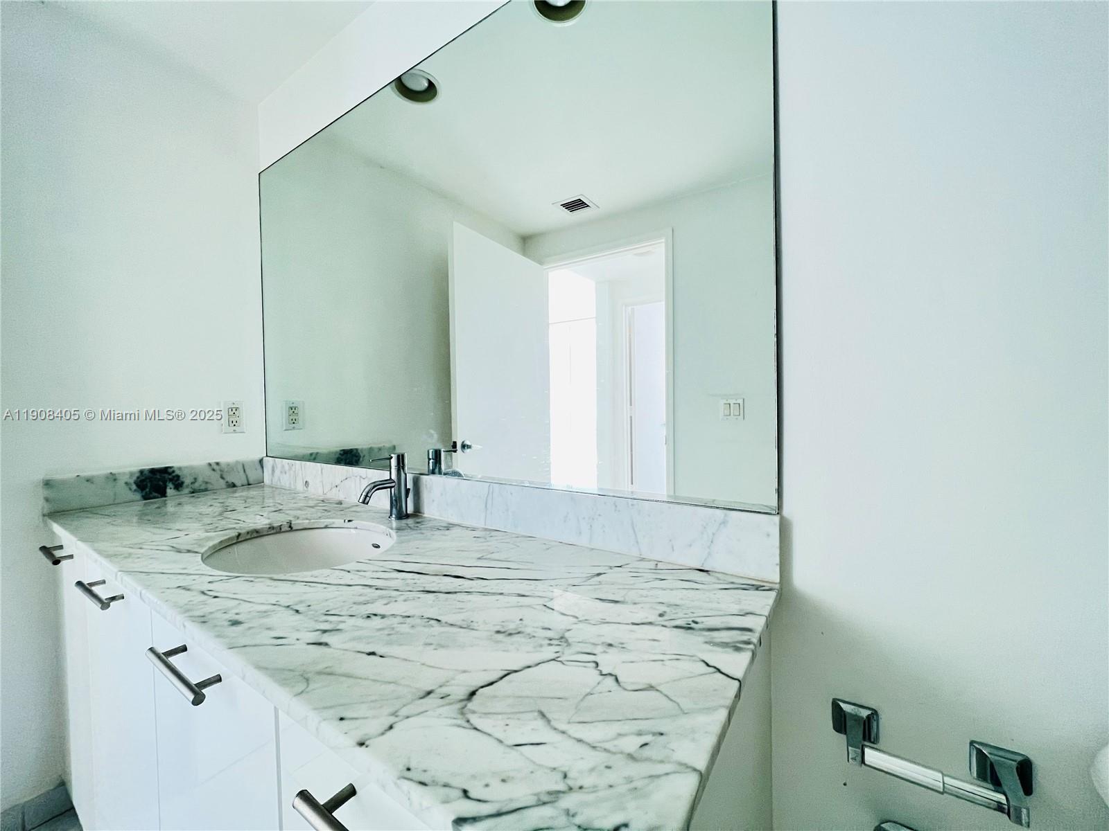 951 Brickell Avenue, Unit 2407 Miami, FL 33131 - Photo 16 of 19 a bathroom with a granite countertop sink and a mirror
