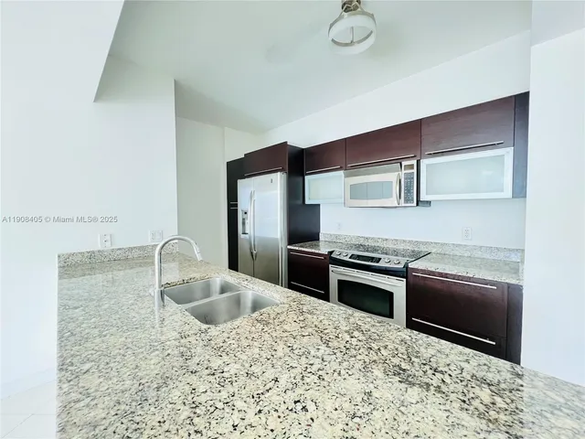 a kitchen with stainless steel appliances granite countertop a sink stove and refrigerator