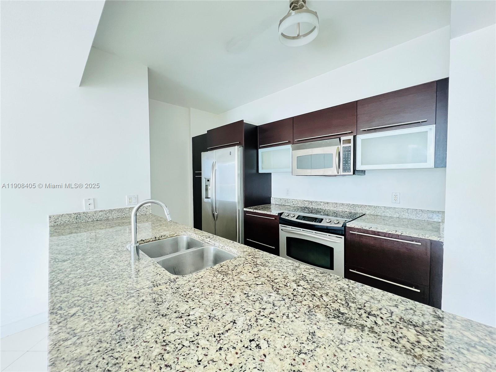 951 Brickell Avenue, Unit 2407 Miami, FL 33131 - Photo 8 of 19 a kitchen with stainless steel appliances granite countertop a sink stove and refrigerator