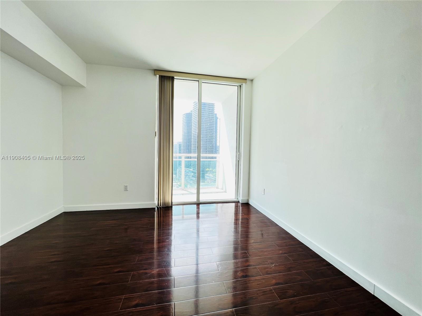 951 Brickell Avenue, Unit 2407 Miami, FL 33131 - Photo 10 of 19 an empty room with wooden floor and windows