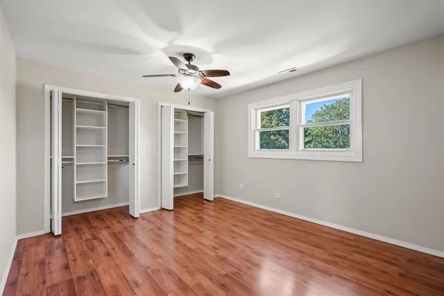 a view of empty room with wooden floor and fan