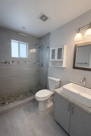 a bathroom with a granite countertop toilet a sink and a mirror