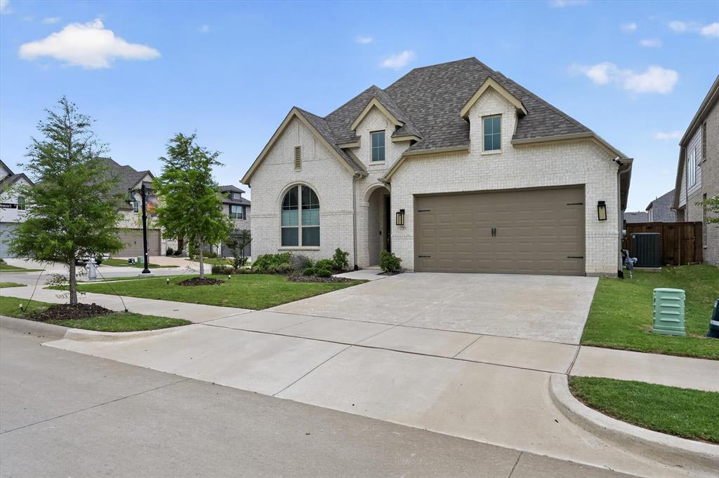 3725 Paradise Way Sherman, TX 75090 - Photo 4 of 26 Light brick facade featuring a composite shingle roof, arched entryway, dormer windows, and a two-car garage with an integrated brown door