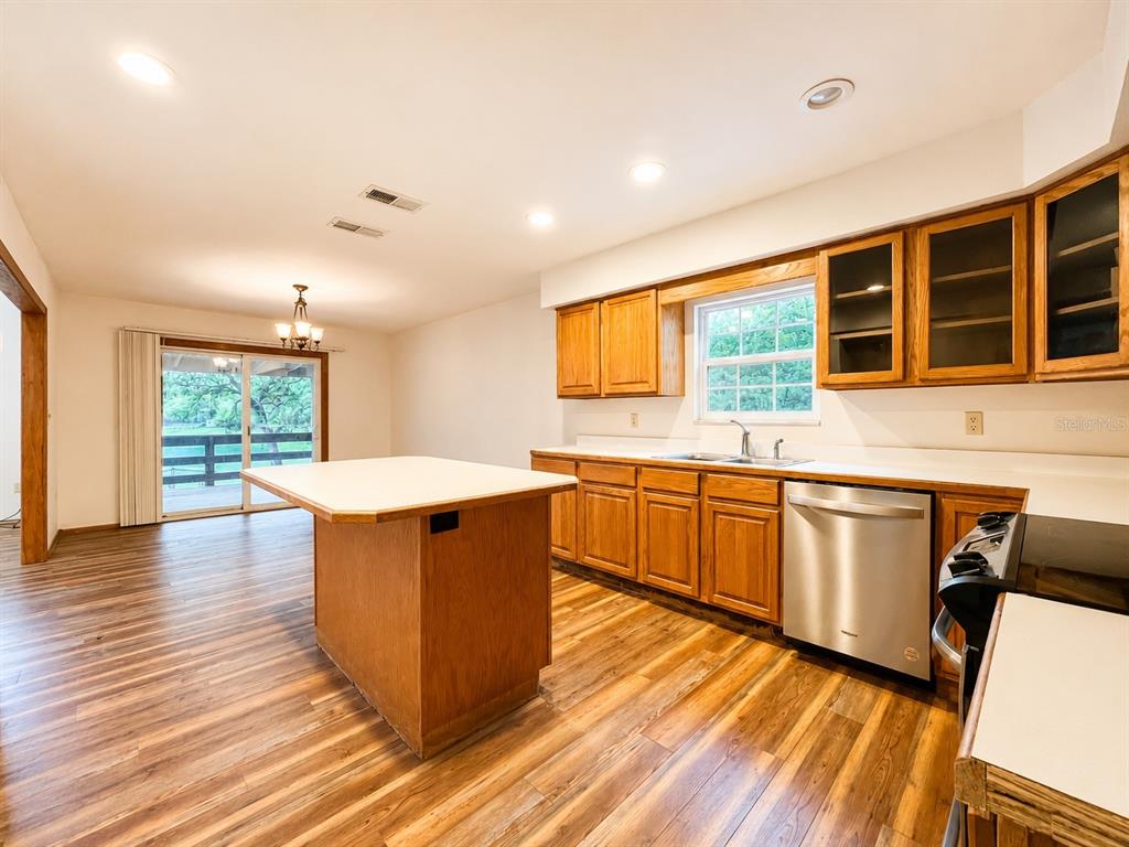 7119 Immokalee Road Keystone Heights, FL 32656 - Photo 17 of 50 a kitchen with stainless steel appliances granite countertop wooden cabinets a sink a stove a refrigerator and island with wooden floors