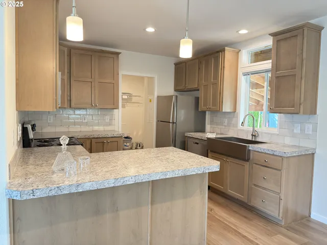 a kitchen with granite countertop a sink a center island stainless steel appliances and cabinets